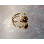 A yellow metal and cherry amber ring, the centrally mounted cherry amber cabochon inset with a