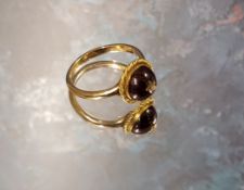 A yellow metal and cherry amber ring, the centrally mounted cherry amber cabochon inset with a