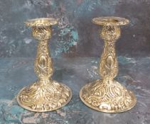 A pair of Victorian style silver boudoir candlesticks, embossed overall with foliage and scrolls,