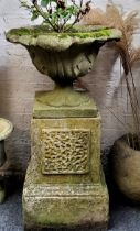 A reconstituted urn on stand, the scrolling acanthus planter sits on an outsplayed socle, stepped