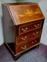 An early 20th century mahogany bureau, the fall front with urns and scrolls, above three drawers,