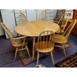 A blonde Ercol oval dining table, two carvers and four chairs (7)