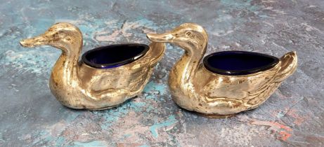 A pair of Edwardian novelty silver salts, as ducks, blue glass liners, 9.5cm wide, Birmingham 1906