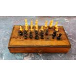 A 19th century travelling chess set and pieces, the board stained, 18cm wide, c.1890