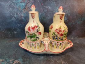 A French Faience oil and vinegar set, painted with stylised flowers and foliage, in colours, 20cm