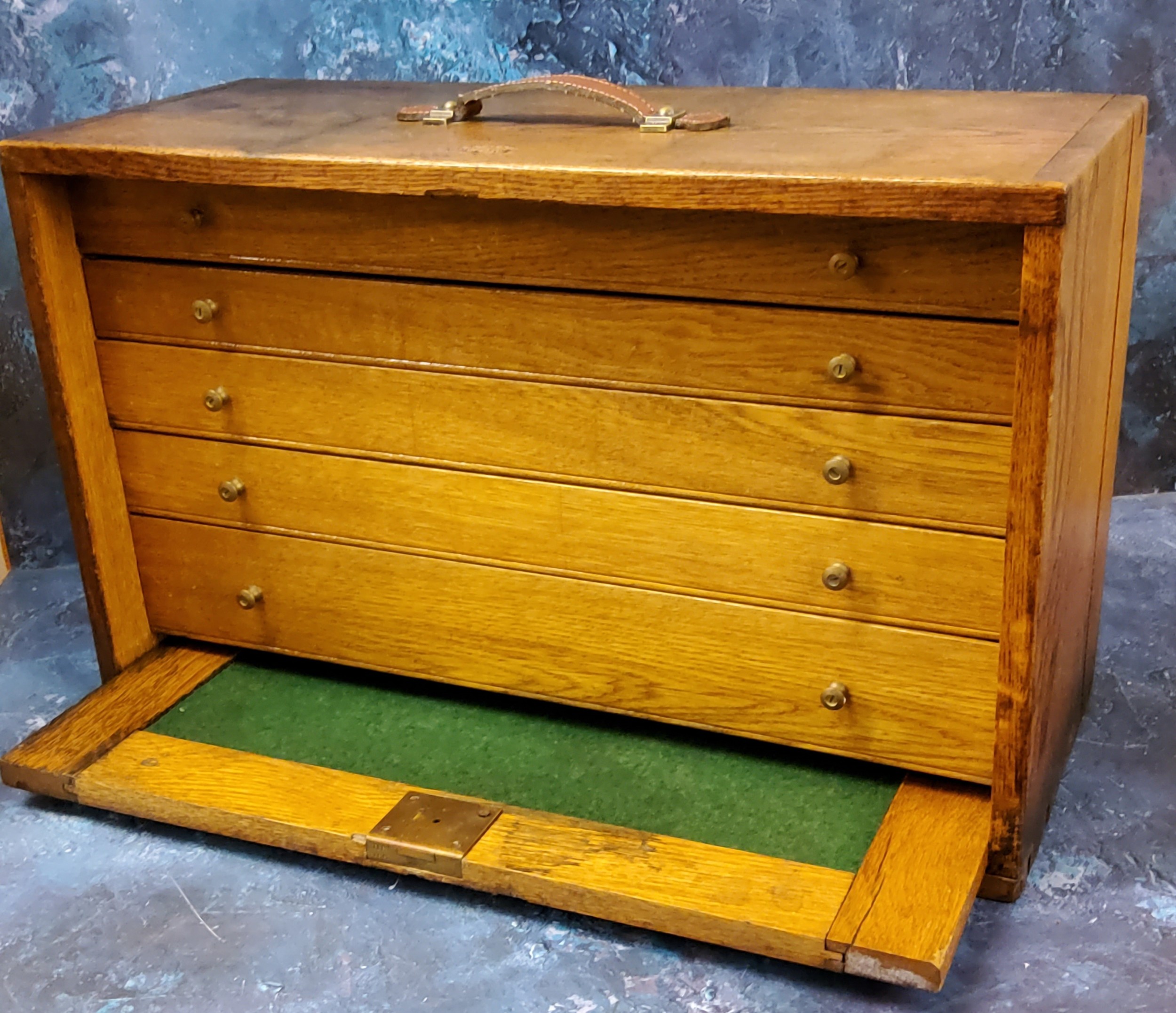 An early 20th century oak tabletop collectors cabinet, the fall fronts, enclosing five graduated