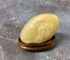 A Chinese jade carving, of a Buddha holding a peach, hardwood stand, 5cm wide