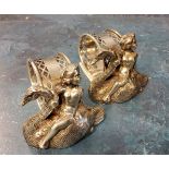 A pair of plated novelty napkin rings, cast with cherubs riding swans, 7cm wide