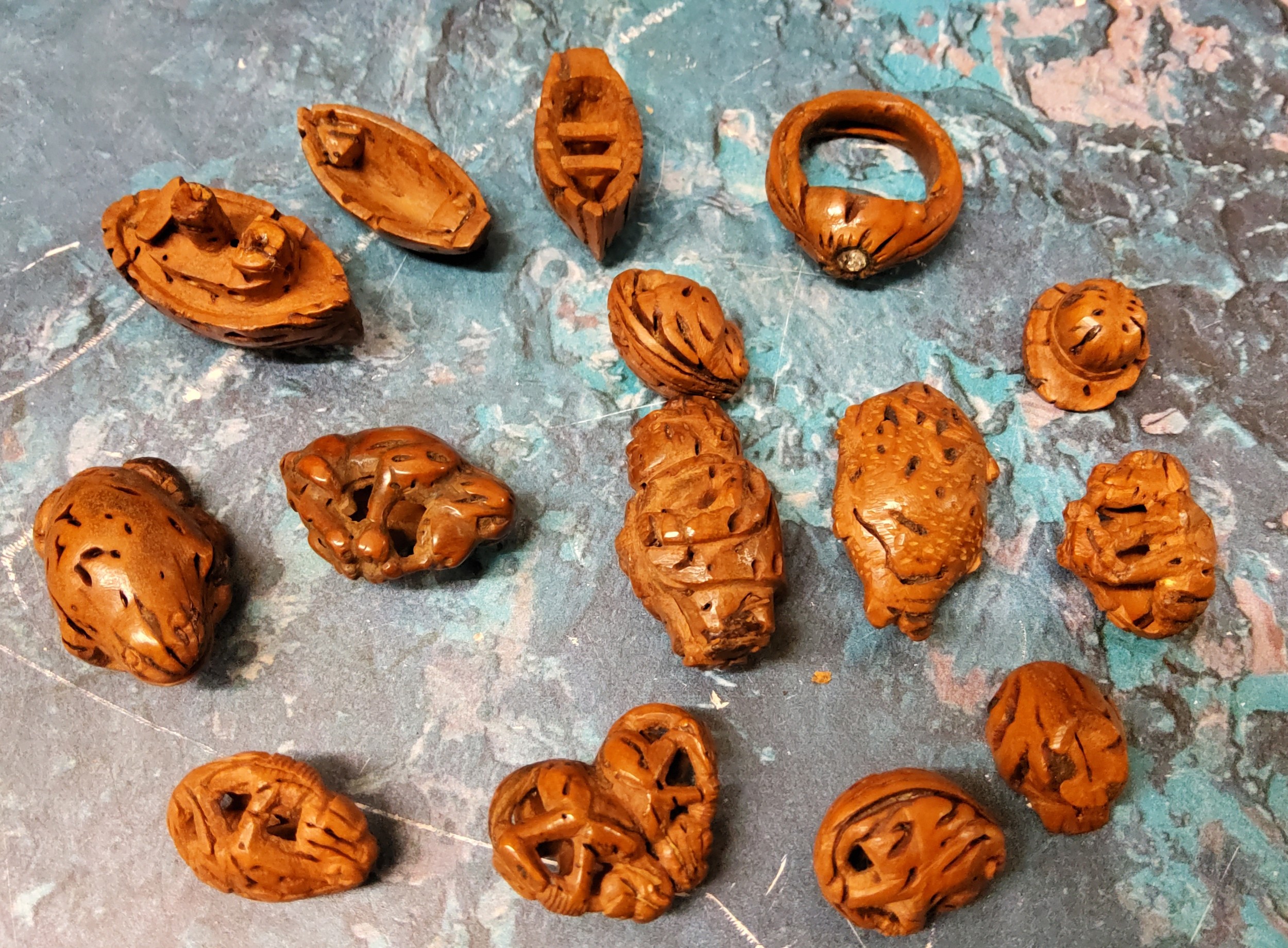 A collection of 19th century carved peach stones, as a ship, bowler hat, rotund figure, etc