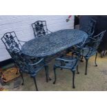 A modern outdoor patio table and chairs, painted in green, cast with flowers and decorative