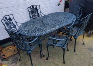 A modern outdoor patio table and chairs, painted in green, cast with flowers and decorative