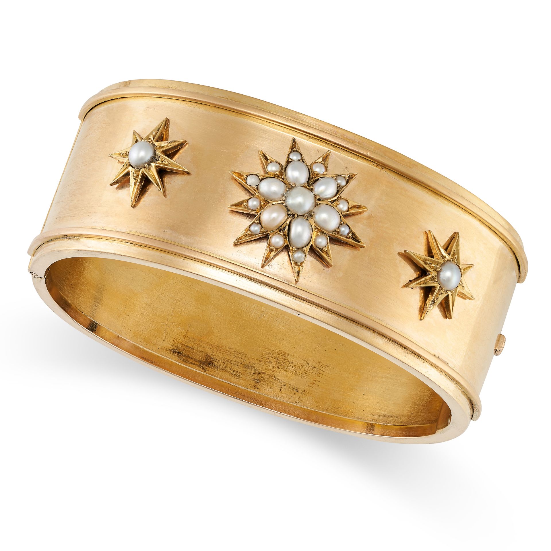 AN ANTIQUE PEARL BANGLE in yellow gold, with three applied star motifs set with pearls, no assay ...