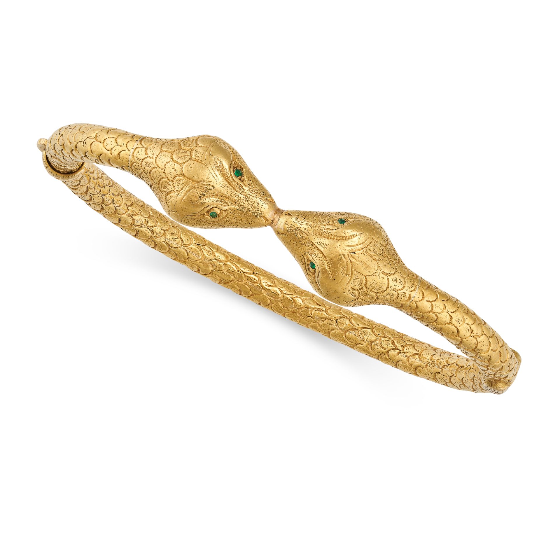 AN EMERALD SNAKE BANGLE in high carat yellow gold, modelled as a two headed snake, each head set ...