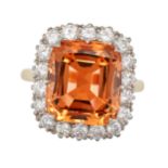 AN IMPERIAL TOPAZ AND DIAMOND CLUSTER RING in 18ct yellow gold, set with an octagonal step cut im...