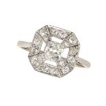 AN ART DECO DIAMOND DRESS RING set with an old cut diamond in a border of further old cut diamond...