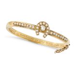 AN ANTIQUE EDWARDIAN PEARL HORSESHOE BANGLE in yellow gold, the hinged bangle with a horseshoe mo...