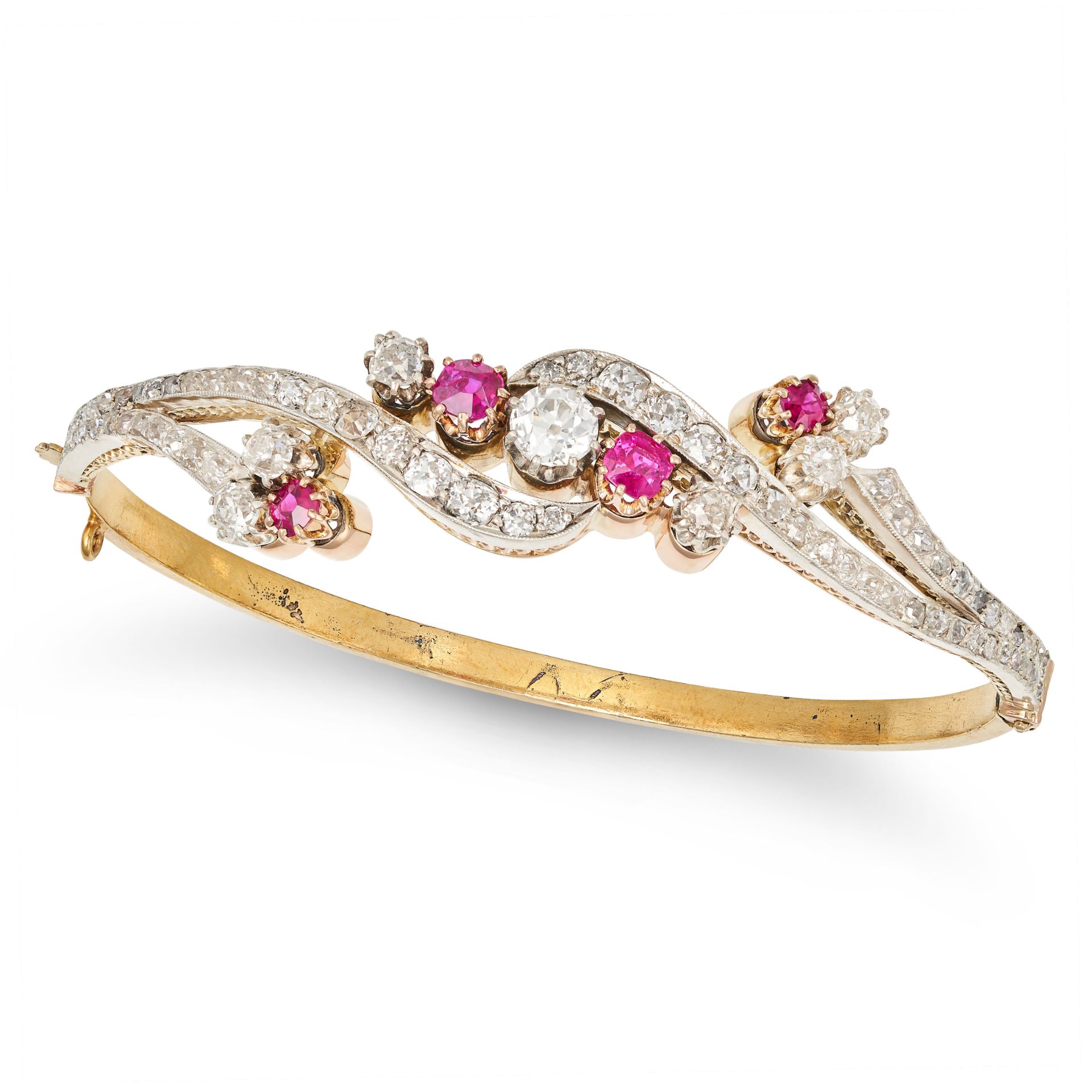 AN ANTIQUE RUBY AND DIAMOND BANGLE in yellow gold, the scrolling hinged bangle set with round cut...