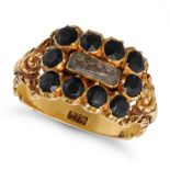 AN ANTIQUE JET MOURNING RING in yellow gold, set with a glass panel containing hairwork in a bord...