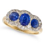 A SAPPHIRE AND DIAMOND RING in yellow and white gold, set with three oval cut sapphires in a bord...