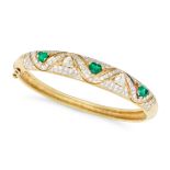 AN EMERALD AND DIAMOND BANGLE in 18ct yellow gold, the hinged bangle set with a row of alternatin...