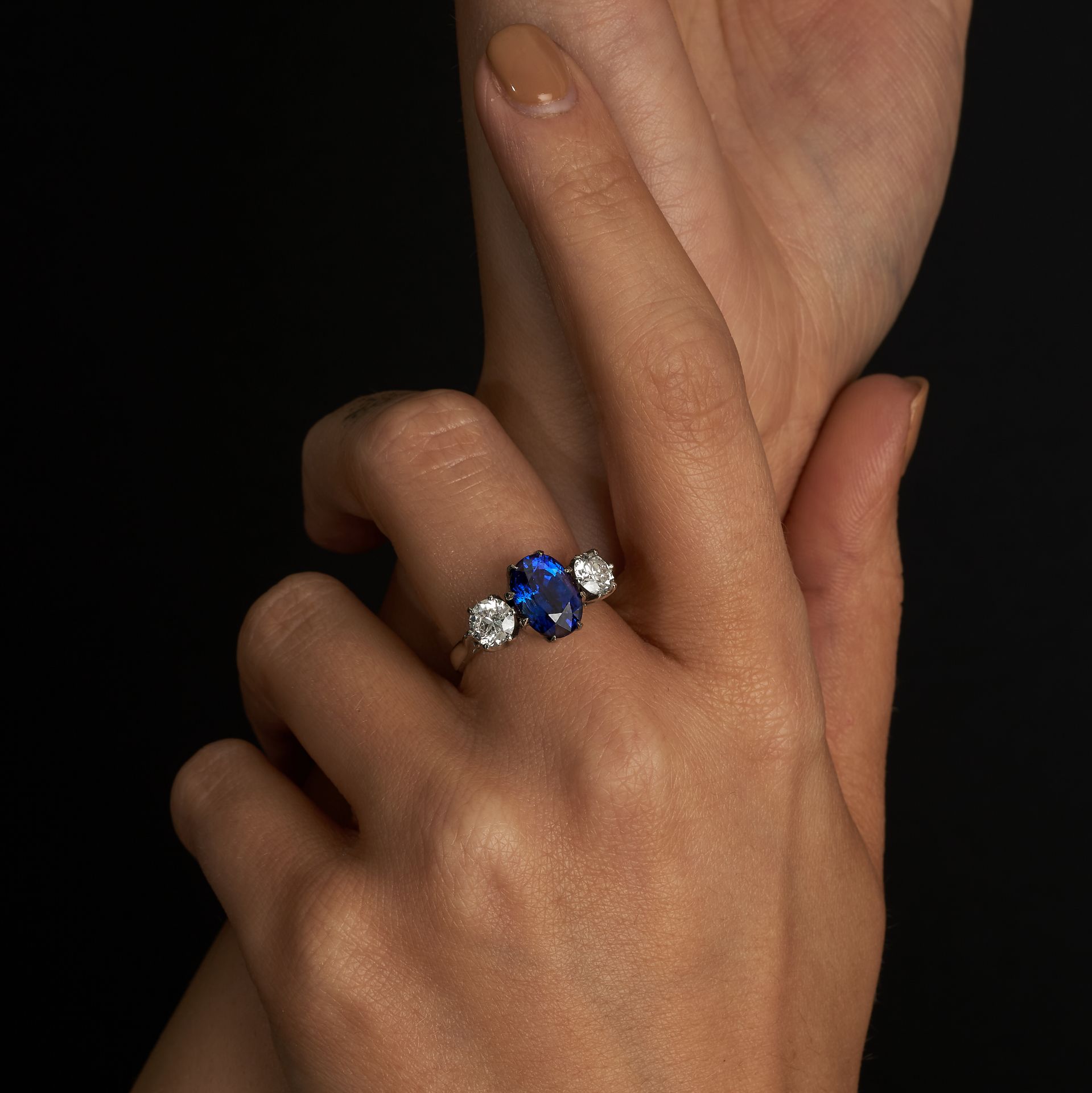 A SAPPHIRE AND DIAMOND THREE STONE RING in platinum, set with an oval cut sapphire of 3.78 carats...