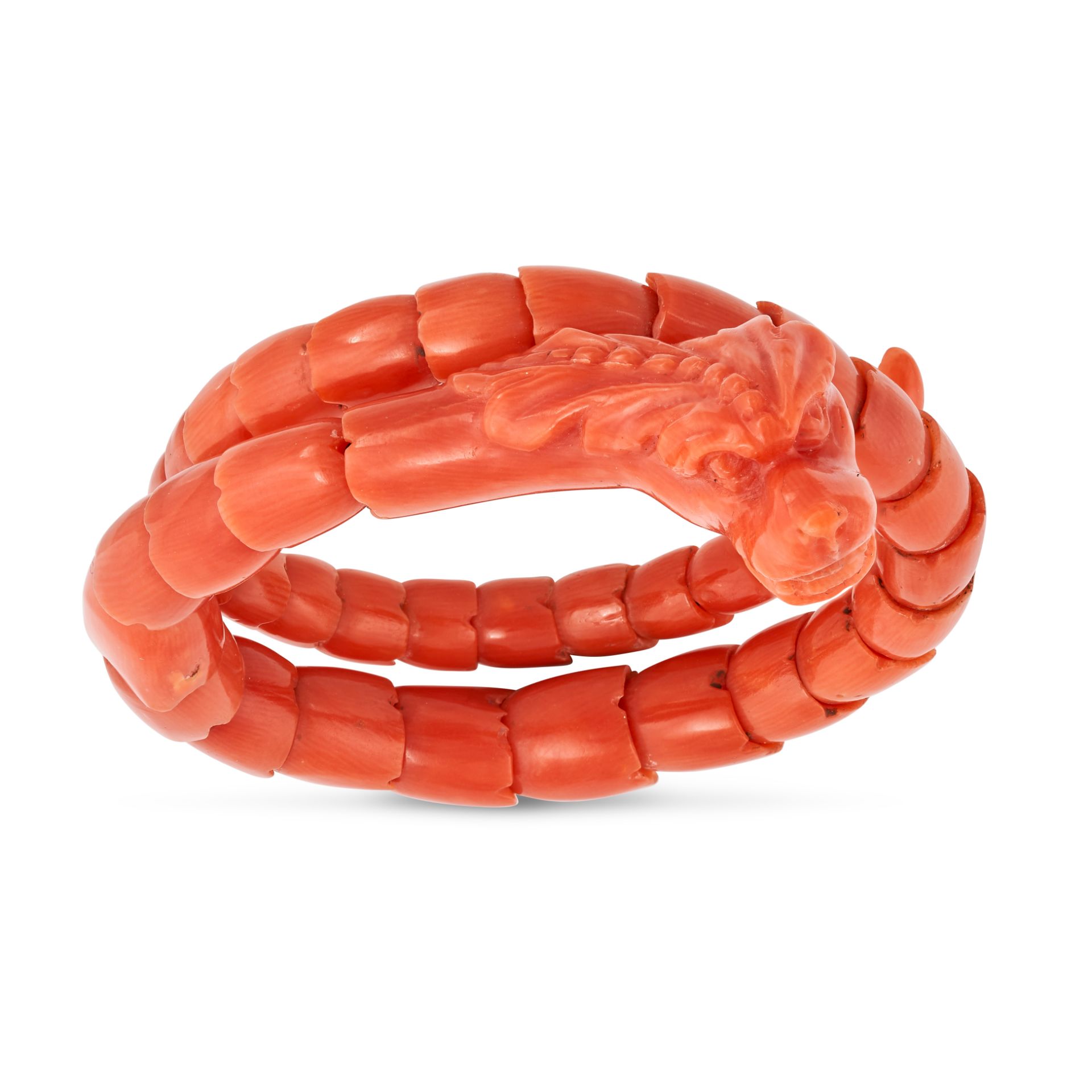 AN ANTIQUE CORAL DRAGON BRACELET designed as a coiled dragon, the body, head, and tail made from ...