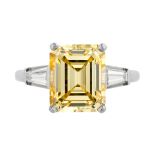 A 5.46 CARAT TREATED FANCY INTENSE YELLOW DIAMOND RING in platinum, set with an emerald cut yello...