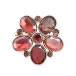 AN ANTIQUE GARNET FLOWER BROOCH in 9ct rose gold, set with oval and round cut garnets forming a s...