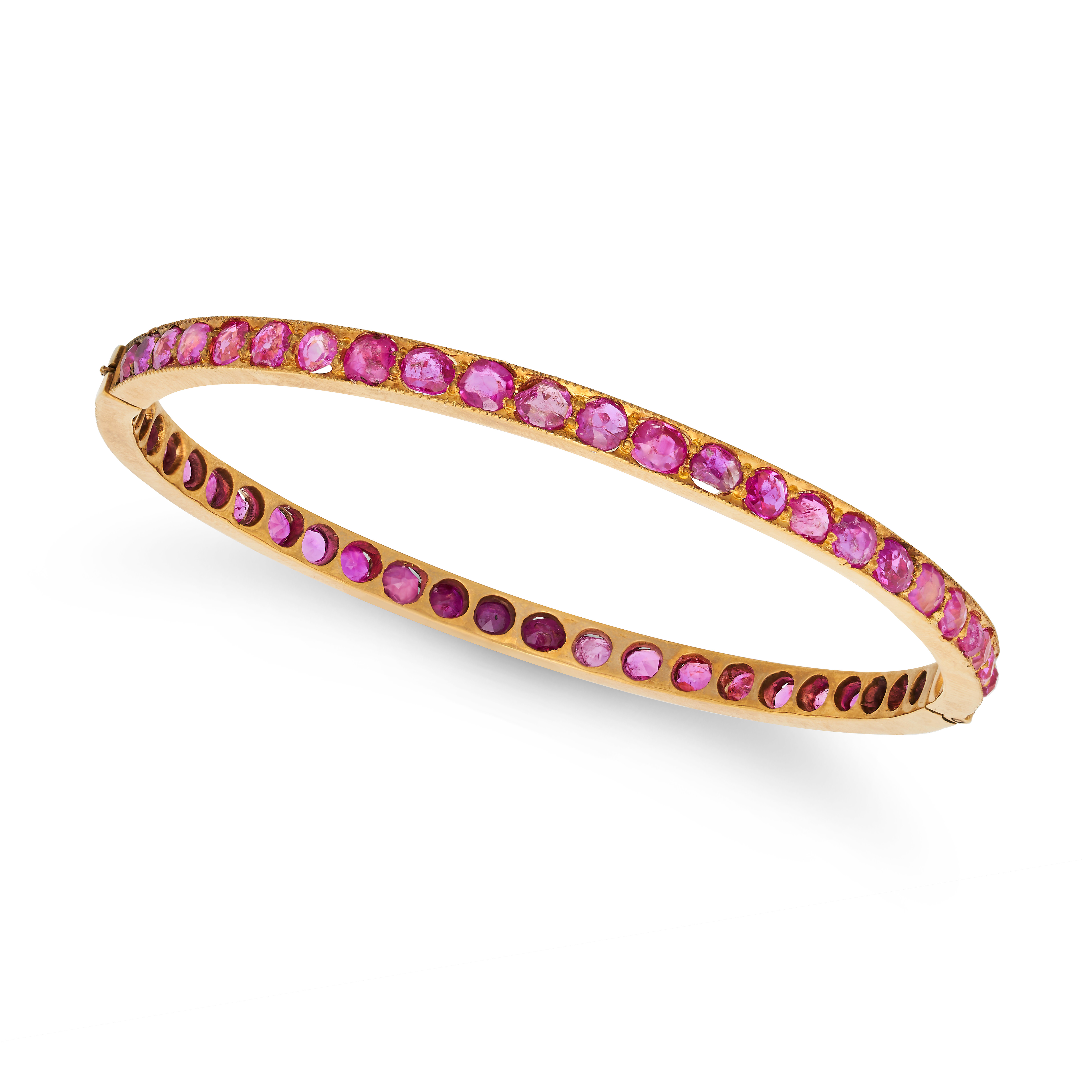 A RUBY BANGLE in 18ct yellow gold, the hinged bangle set all around with a row of oval and round ...