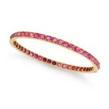 A RUBY BANGLE in 18ct yellow gold, the hinged bangle set all around with a row of oval and round ...