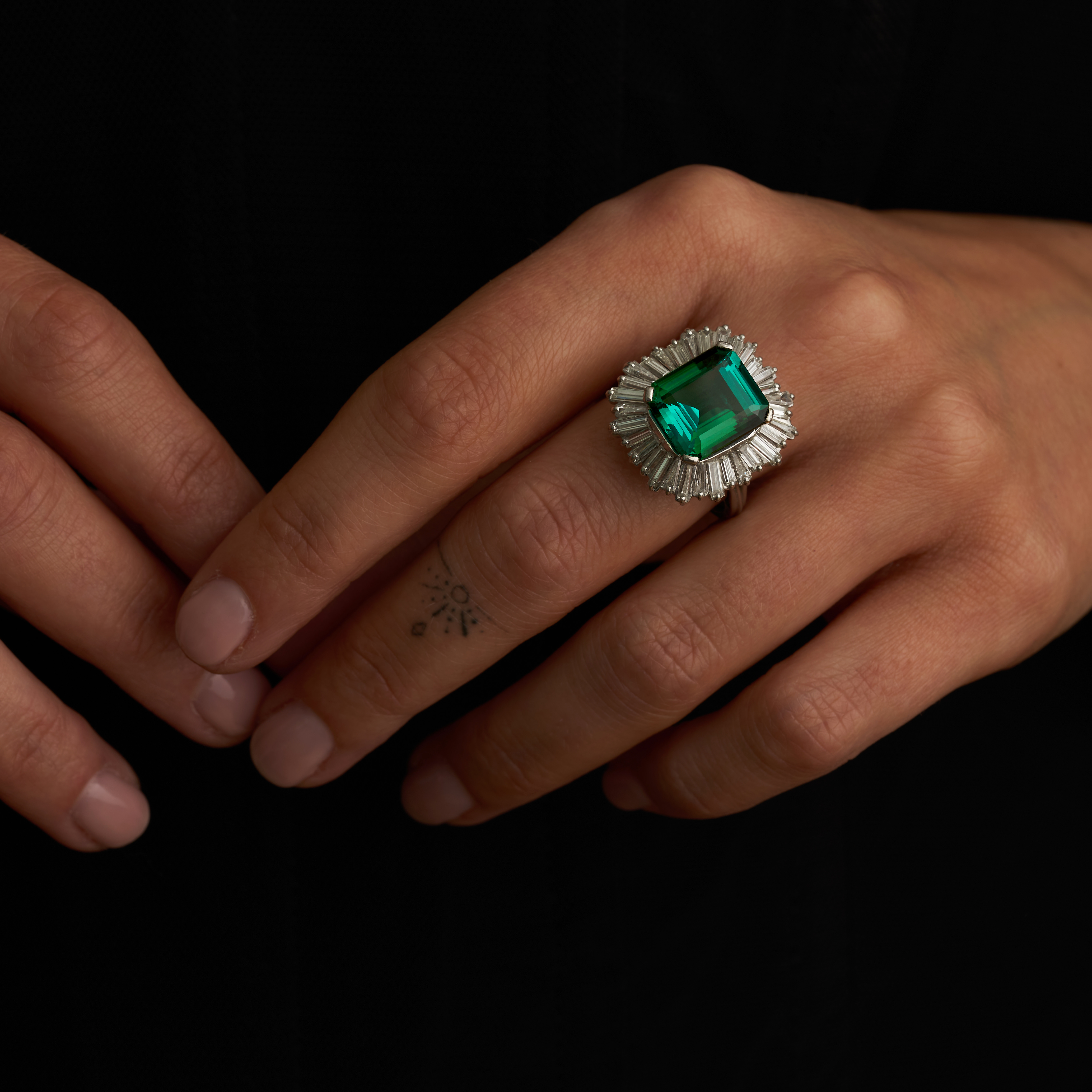 A GREEN TOURMALINE AND DIAMOND BALLERINA RING in platinum, set with an octagonal step cut green t...