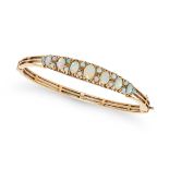 AN OPAL BANGLE in 9ct yellow gold, the hinged bangle set with a row of graduated oval cabochon op...