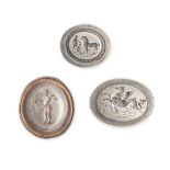 THREE UNMOUNTED SILVER INTAGLIOS depicting Cupid burning a butterfly, Cupid riding a seahorse and...