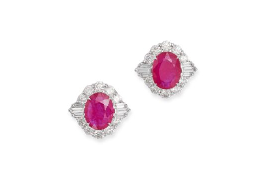 A PAIR OF RUBY AND DIAMOND EARRINGS in 18ct white gold, each set with an oval cut ruby in a clust...