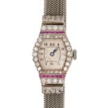 AN ART DECO RUBY AND DIAMOND COCKTAIL WATCH in platinum, the off-white tonneau dial with guilloch...