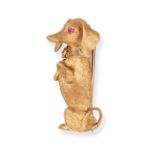 A RUBY DACHSHUND BROOCH in 18ct yellow gold, designed as a dachshund standing on its hind legs, t...