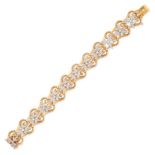 A DIAMOND BRACELET in yellow gold, each link in a scrolling design set with a trefoil cluster of ...