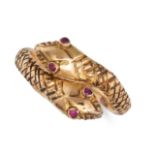 A RUBY SNAKE RING in yellow gold, designed as two coiled snakes, the eyes set with round cut rubi...