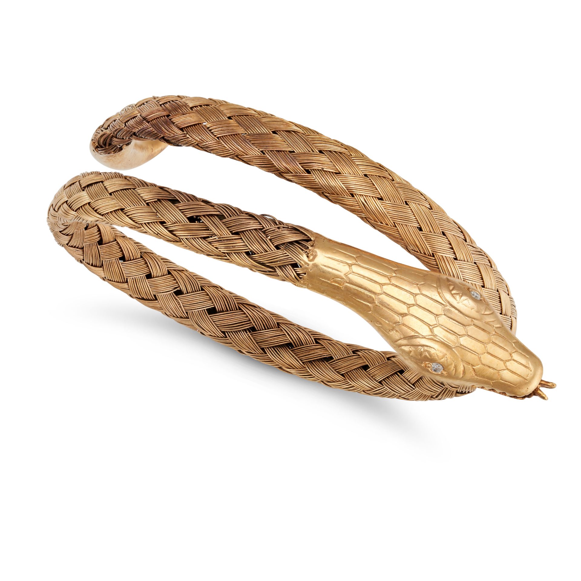 A DIAMOND SNAKE BANGLE in yellow gold and base metal, designed as a coiled snake, the eyes of the...