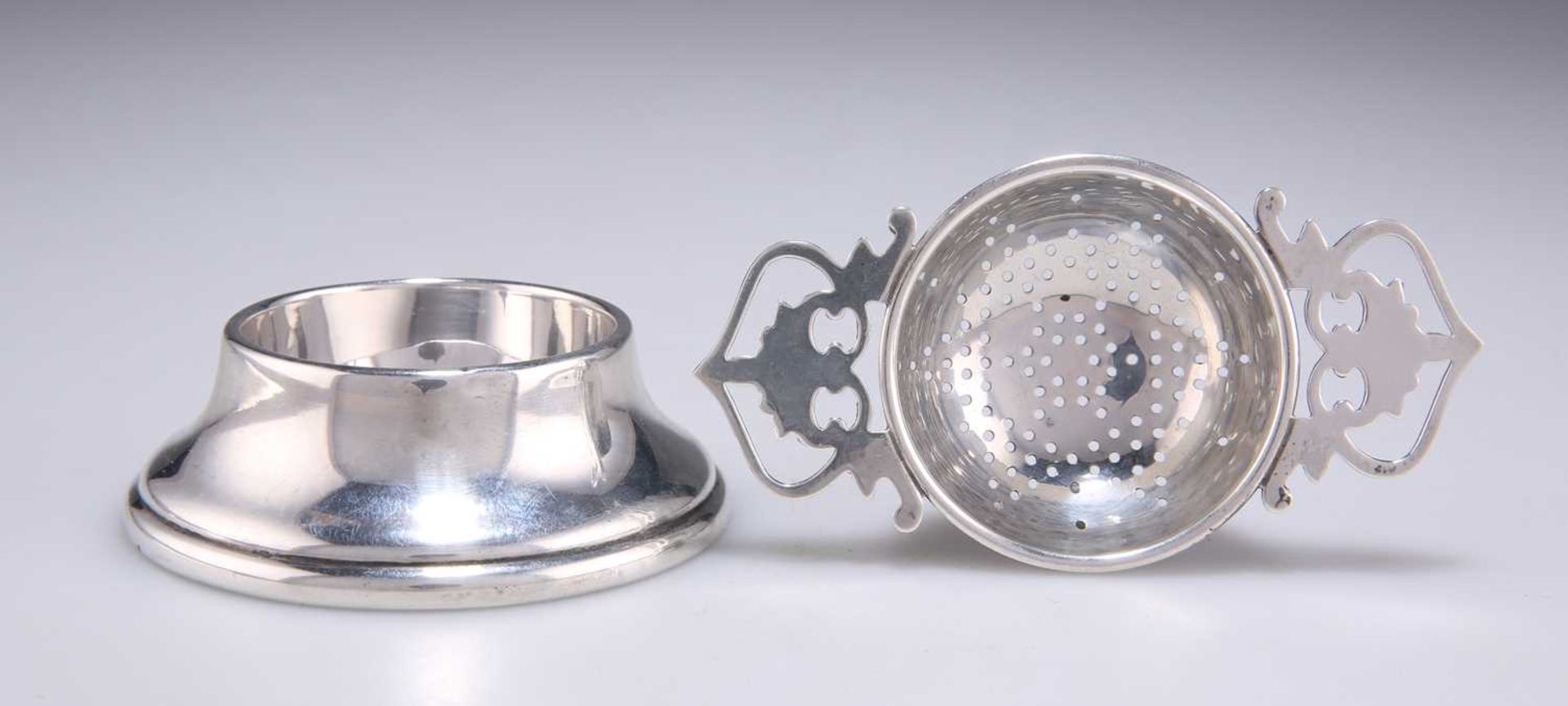 A GEORGE VI SILVER TEA STRAINER ON STAND