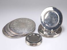 A GROUP OF FIFTEEN SILVER-PLATED COASTERS, TOGETHER WITH A SET OF FOUR SILVER-PLATED TABLE MATS