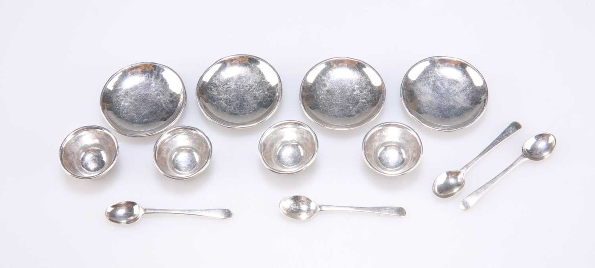 A SET OF FOUR SILVER TOY TEA BOWLS, SAUCERS AND SPOONS