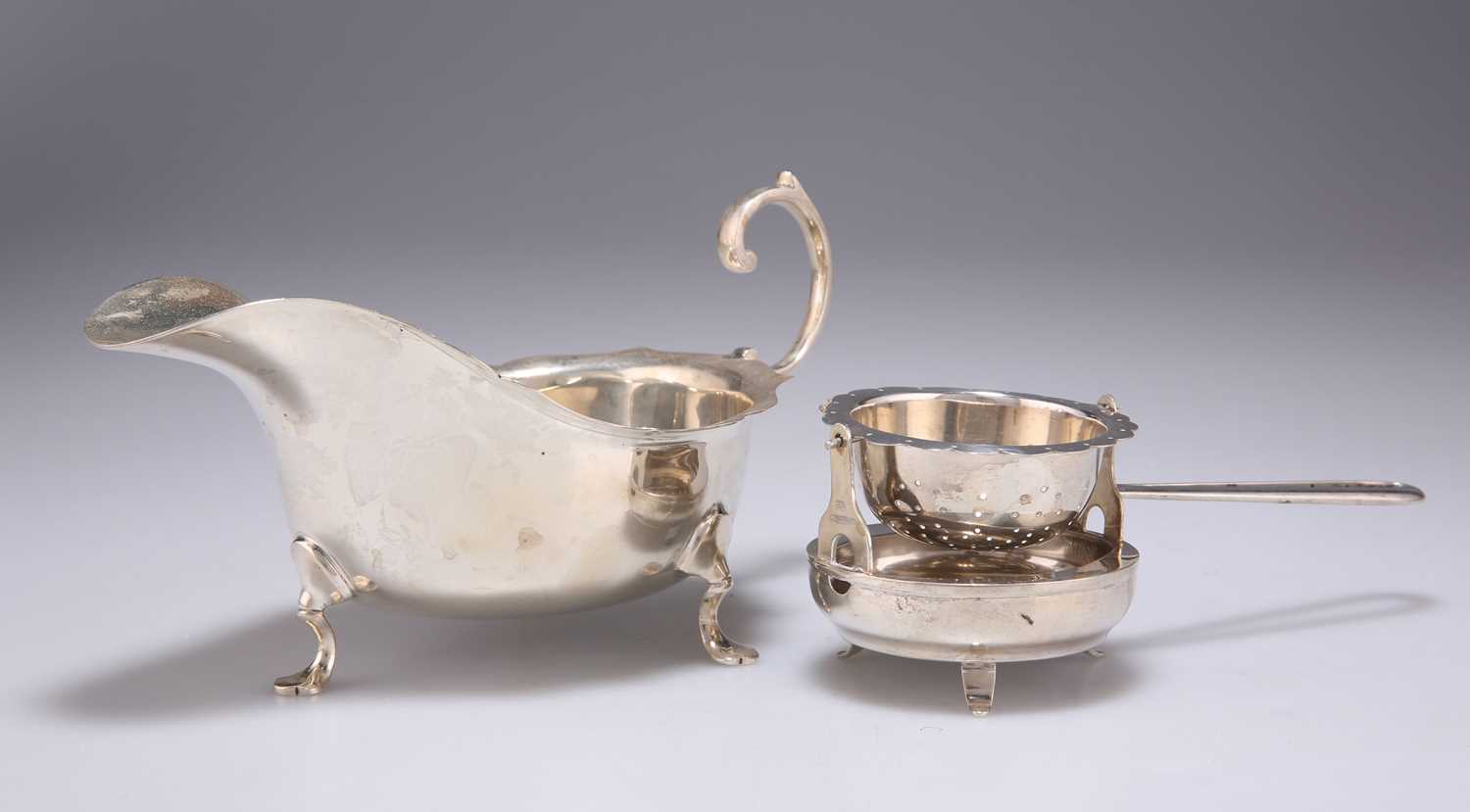 A GEORGE V SILVER SAUCE BOAT, AND A FOREIGN SILVER TEA STRAINER