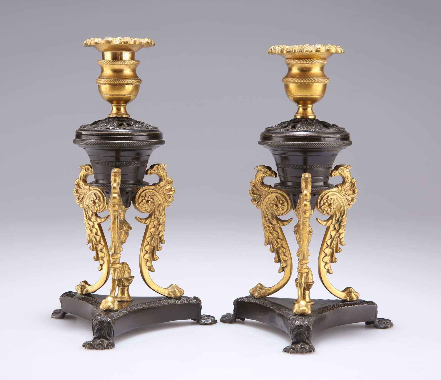 A PAIR OF REGENCY PATINATED AND GILT BRONZE DWARF CANDLESTICKS, IN THE MANNER OF CHENEY, LONDON