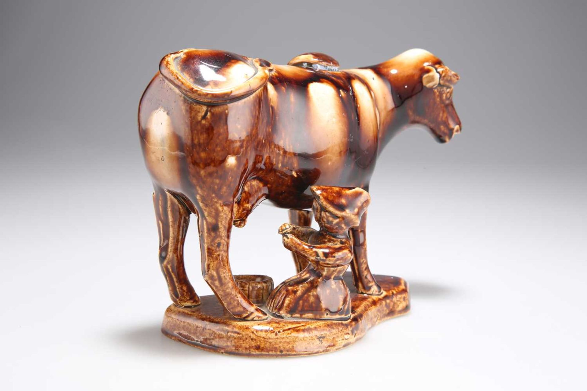 A 19TH CENTURY STAFFORDSHIRE TREACLE-GLAZED POTTERY COW CREAMER AND MILKMAID GROUP - Image 2 of 3