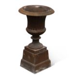 A SMALL CAST IRON URN ON STAND