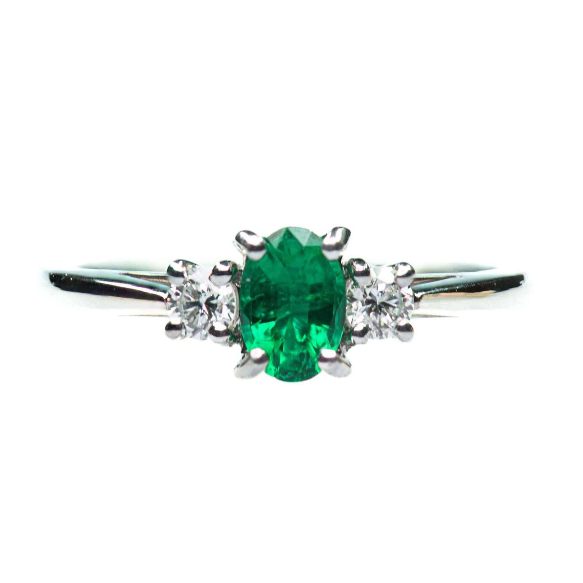 A PLATINUM EMERALD AND DIAMOND THREE STONE RING