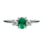 A PLATINUM EMERALD AND DIAMOND THREE STONE RING