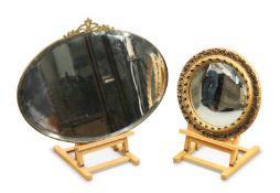 AN EARLY 20TH CENTURY BRASS-FRAMED OVAL MIRROR AND A GILT-COMPOSITION CIRCULAR MIRROR