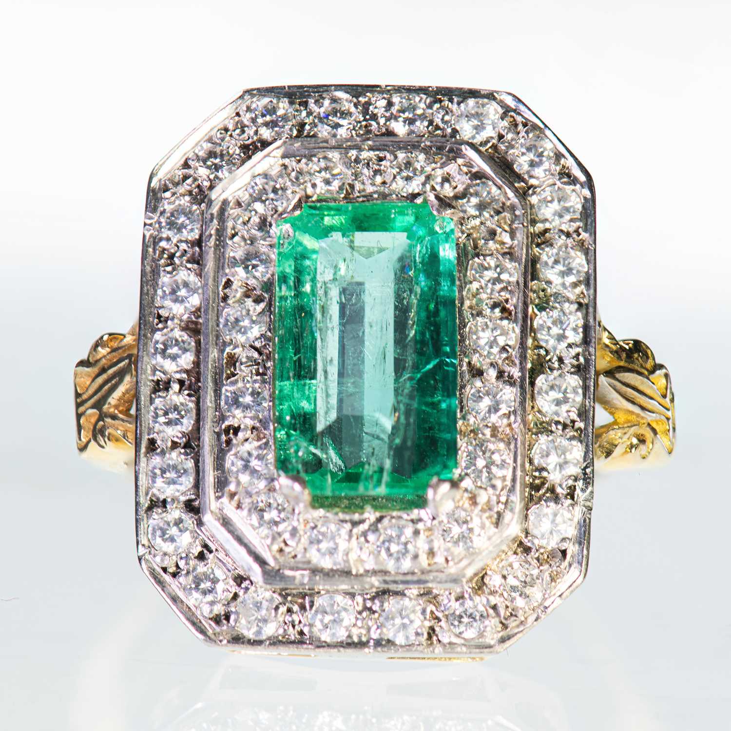 AN 18 CARAT GOLD EMERALD AND DIAMOND CLUSTER RING